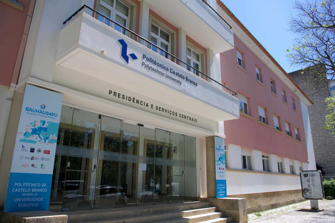 The entrance of the Polytechnic University of Castelo Branco, featuring glass doors, stairs to access it, and two banners promoting the BAUHAUS4EU Alliance.
