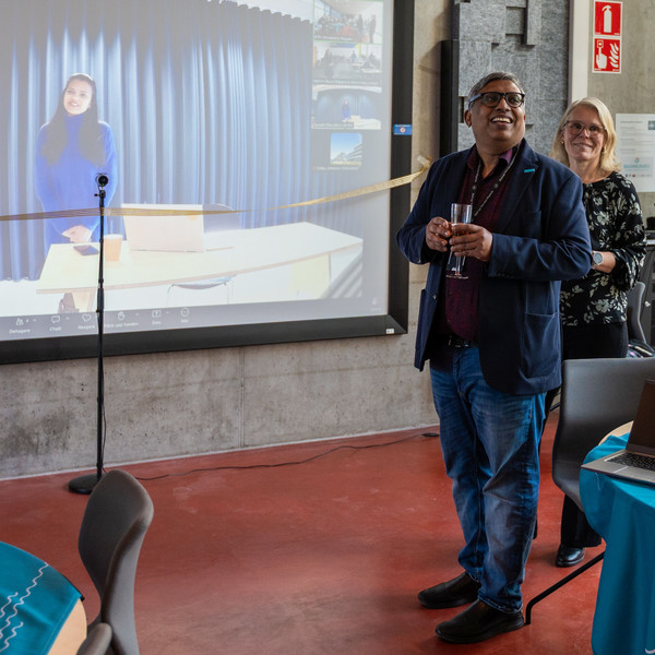 Two people stand in front of a large screen showing an online connection during a BAUHAUS4EU event.