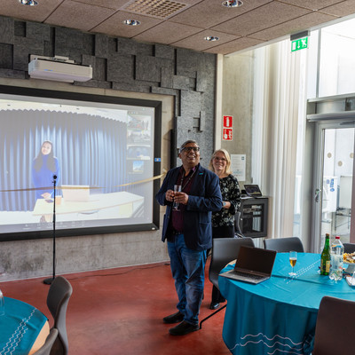 Two people stand in front of a large screen showing an online connection during a BAUHAUS4EU event.