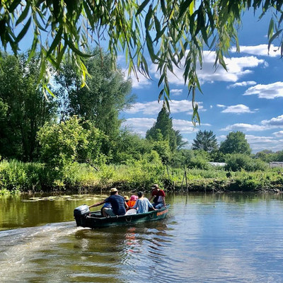 A small boat with people rowing on the Somme River on a summer day