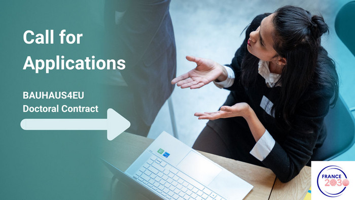Woman in business attire is sitting at a desk, talking to a colleague